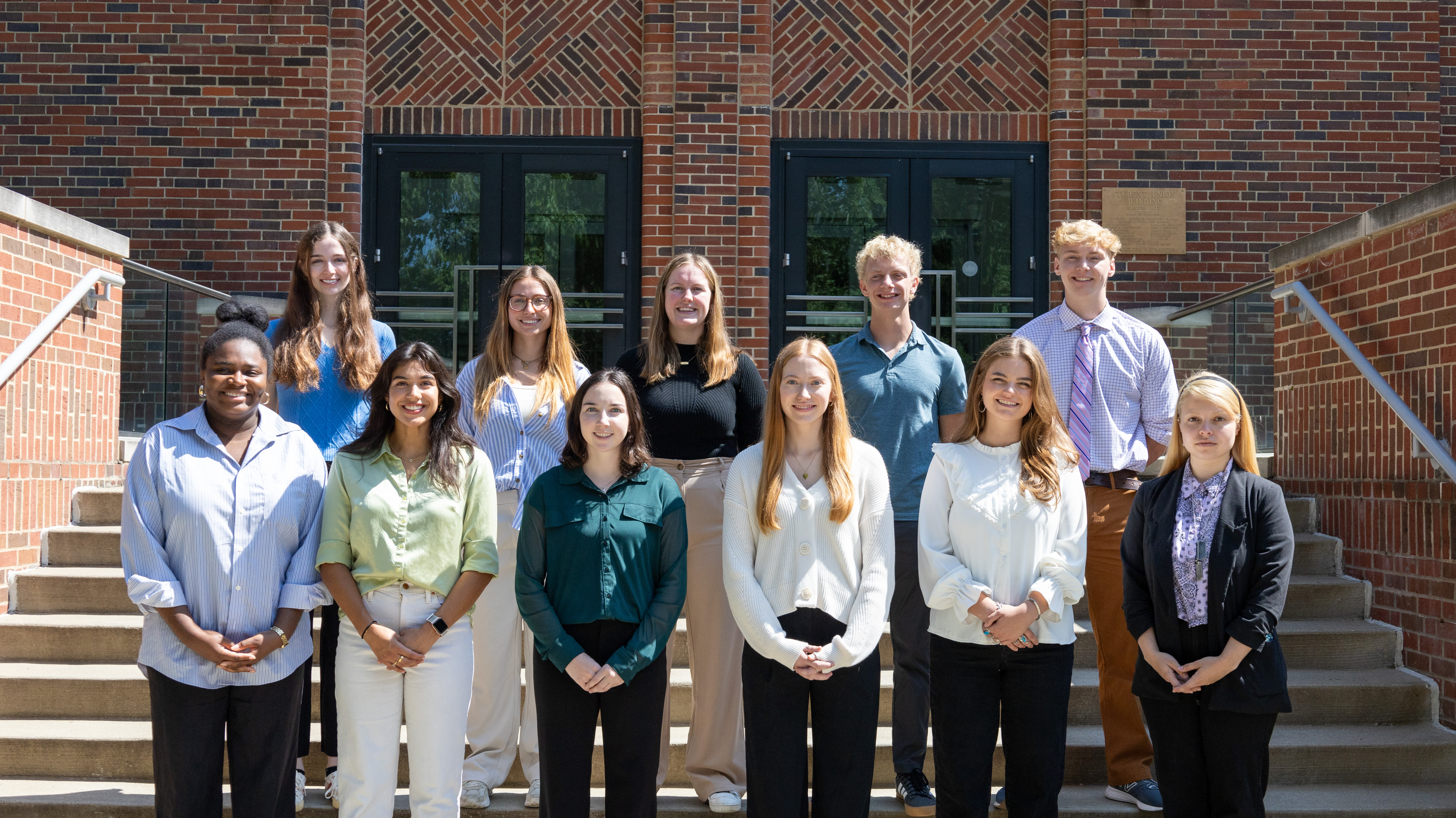 Group photo of the 2024-2025 interns standing on the steps around the back of the Gatton Student Center.