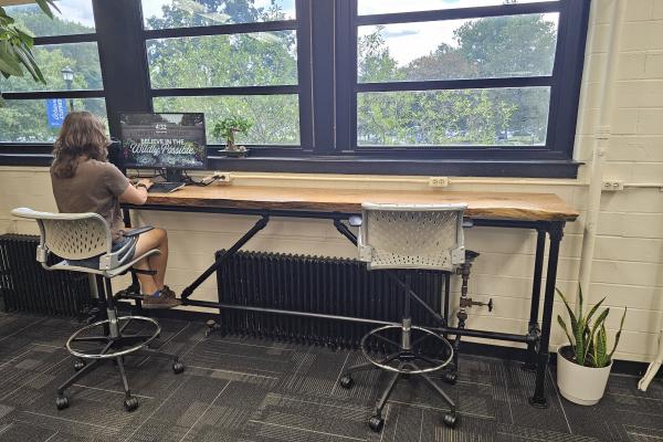 Student seated at high-top work bar made from Campus Woods