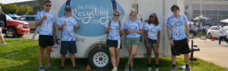 A collection of students in front of a University of Kentucky Recycling trailer.