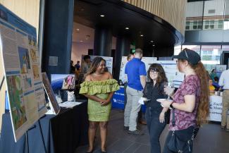 Showcase attendees stand near sustainability research poster