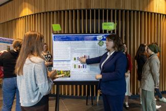 Student describes research poster to showcase attendee