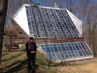 Man stands in front of house covered in solar panels