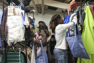 Two students browse clothing racks at the thrifty cat campus free store