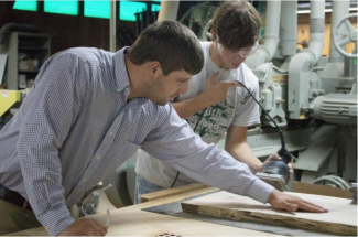 Two men working on sanding down wood in a woodshop
