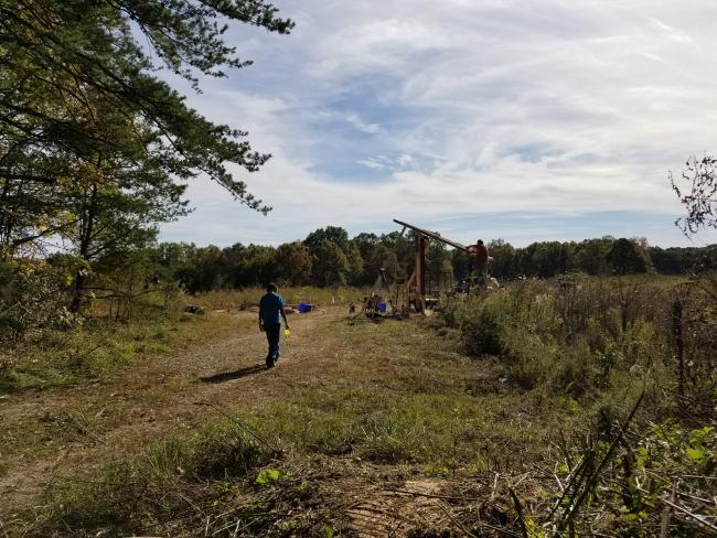 A mountaintop removal site at sunset with two students working on building the entry sign