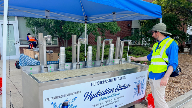 UK staff member refills water at the fall move-in hydration station