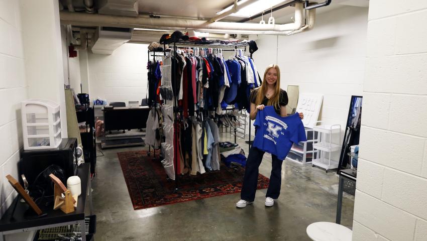 Student poses next to clothing rack in campus free store