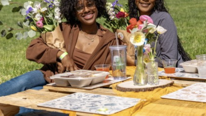 Students pose outdoors with flower bouquet at picnic