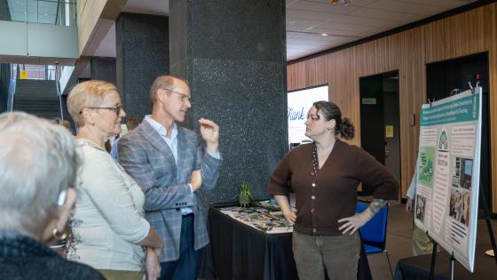 Group of people talk in front of a poster at a tabling event